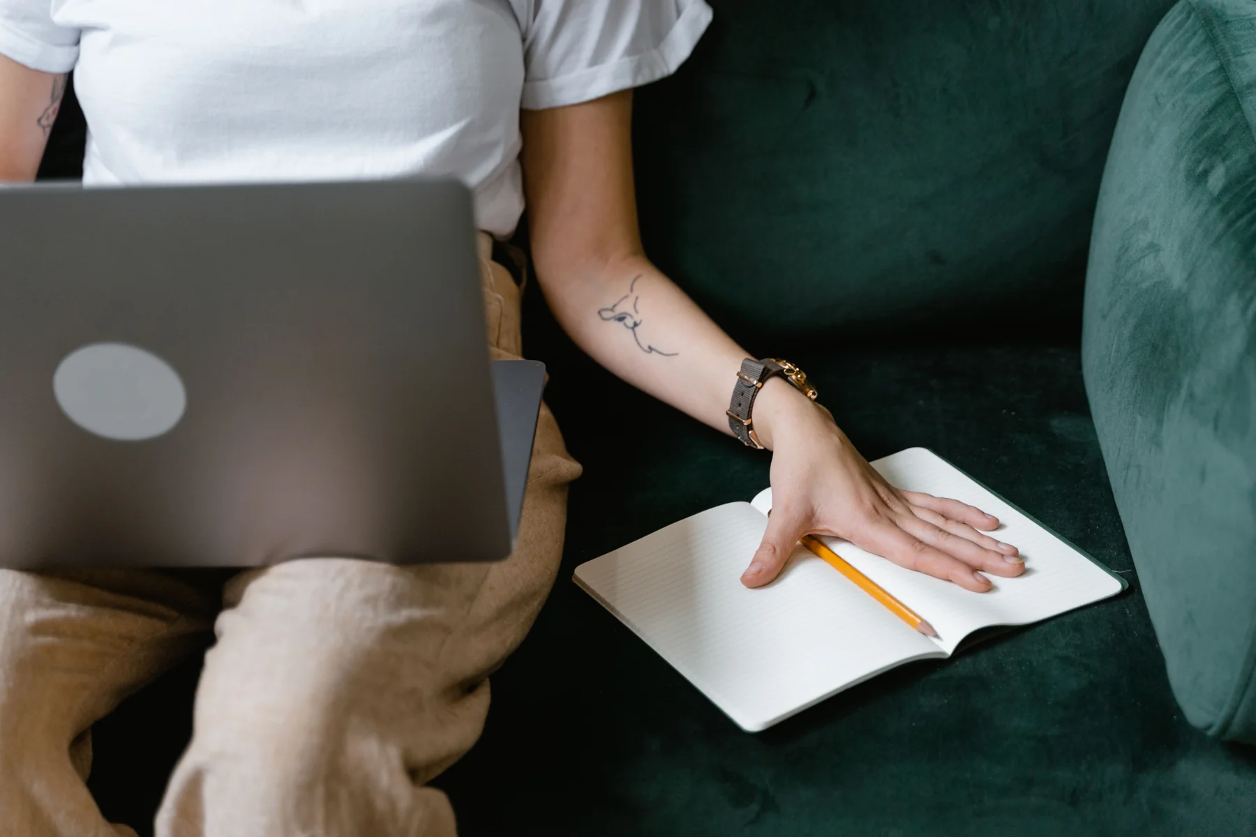 Woman working calmly with a laptop and notebook on a sofa